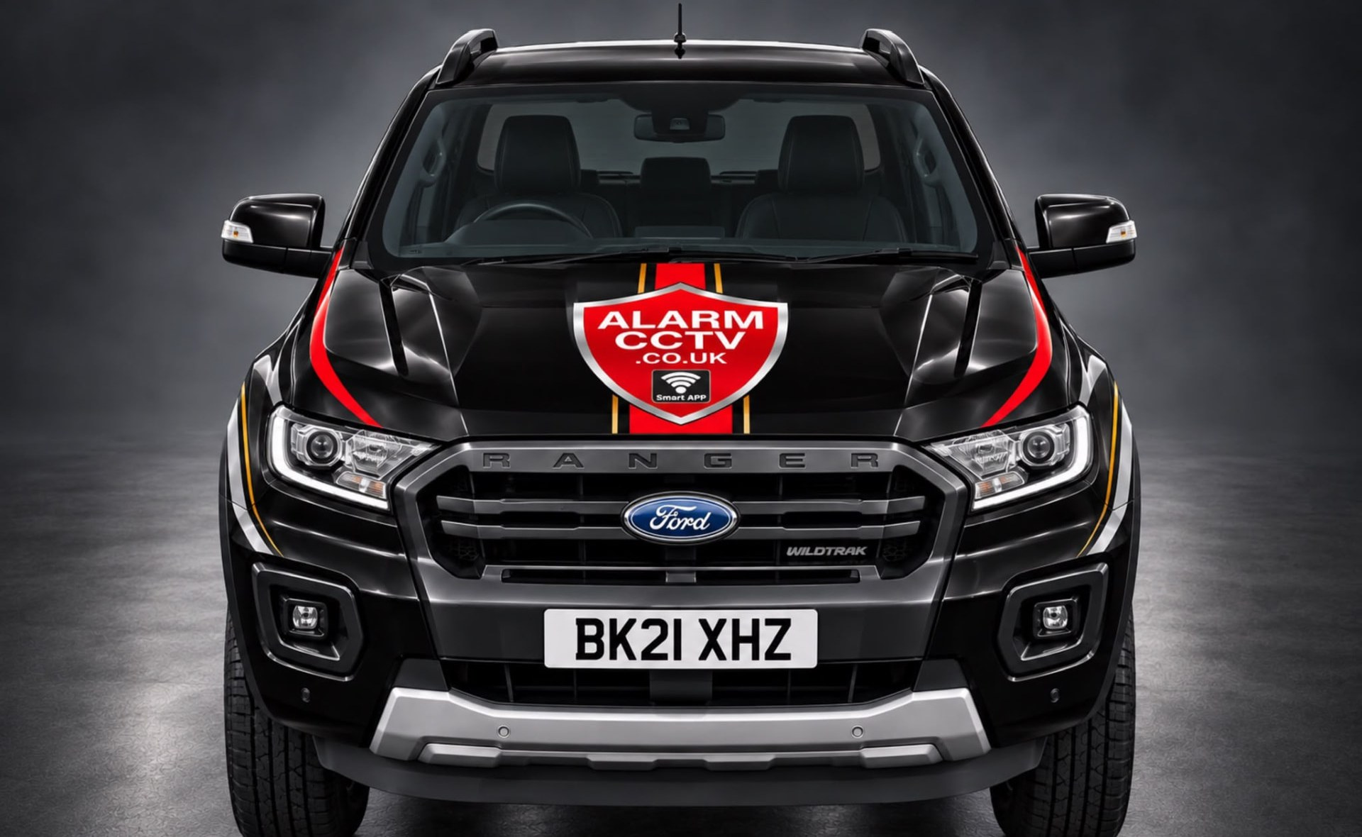 Front of the black AlarmCCTV Ford Ranger Wildtrak service vehicle with the red AlarmCCTV.co.uk Smart App shield on the bonnet